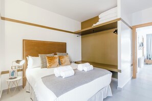 A hotel room with a bed, a bedside table, a lamp, a wardrobe, and a mirror.