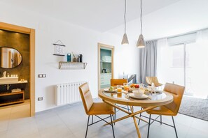 A modern dining area with a round table, two chairs, and a breakfast setting.