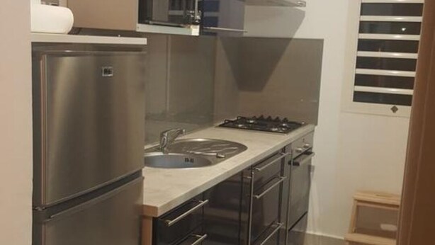 A compact kitchen with stainless steel appliances, a built-in oven, and a sink. - Studio any comfort. (Terre de haut les saintes)