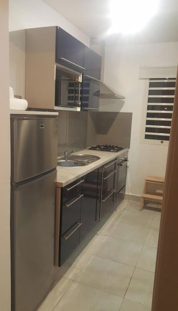 A compact kitchen with a refrigerator, stove, sink, and cabinets.