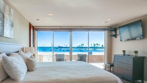 Un dormitorio con una cama grande, televisión, cómoda y vista al mar.