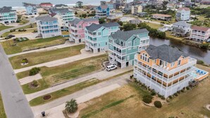 A coastal residential area with multi-story houses featuring balconies and waterfront views. - Oceanview Dog Friendly with Private Pool, Hot Tub, Elevator, Game Room, Theater (Rodanthe)