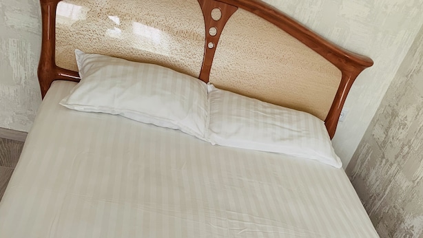 A neatly made bed with white linens, a wooden headboard, and a set of towels on the bed. - Center. 1. 2 km to Deribasovskaya (Odesa)