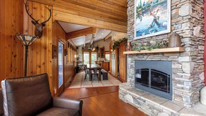 A wooden interior with a stone fireplace, leather furniture, and a deer head mounted on the wall. - Mountaineer Manor- views, hot tub, 3 acres fenced in yard, pool table (Sugar Grove)