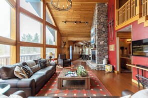 A spacious living area with a large sofa, a coffee table, and a stone fireplace.