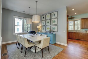A dining area with a table and chairs, a blue kitchen island, and framed artwork on the wall. - 205 Jacana-"The Sandy Pelican" only a few sandy steps (93 yards) to the beach (Hilton Head)