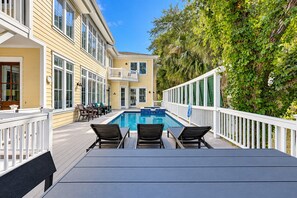 A pool area with a view of a building, outdoor furniture, and a white fence. - 205 Jacana-"The Sandy Pelican" only a few sandy steps (93 yards) to the beach (Hilton Head)