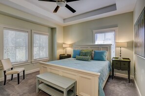 Une chambre à coucher comprenant un lit, deux tables de chevet, un banc, une chaise et un ventilateur de plafond.