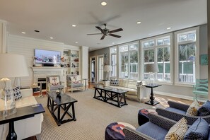 A spacious living room with a fireplace, comfortable seating, and large windows.