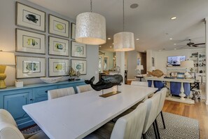 A modern kitchen with a central island, pendant lighting, and framed fish artwork on the wall.