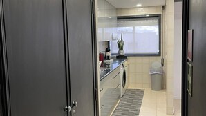 Una cocina moderna con horno integrado, lavadora y ventana con vistas.