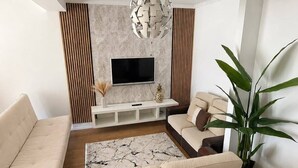 Una sala de estar moderna con un sofá, una mesa de centro, un televisor y una planta decorativa.