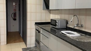 Una cocina moderna con gabinetes grises, un microondas, un lavabo y un extintor.
