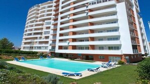 Um hotel de vários andares com piscina e espreguiçadeiras.