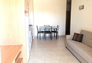 Cozy studio apartment with a kitchenette, dining area, and comfortable seating.