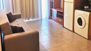 Uma sala de estar com sofá, televisão e máquina de lavar.