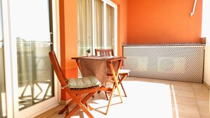 Quarto com paredes laranja, uma mesa de madeira e duas cadeiras de madeira.