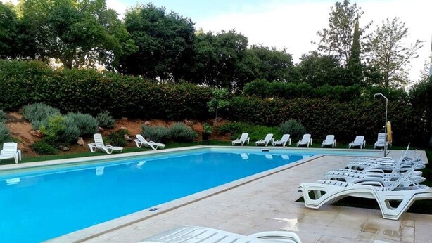 Piscina com espreguiçadeiras e um deck pavimentado.