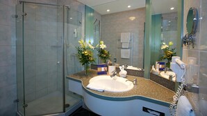 Un baño moderno con cabina de ducha de vidrio, lavamanos con encimera y un espejo grande.