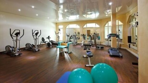 Un gimnasio espacioso con diversos equipos de ejercicio, como cintas de correr, bicicletas estáticas y pesas libres.