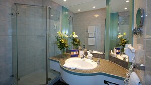 Un baño moderno con cabina de ducha de vidrio, lavamanos con encimera y un espejo grande.