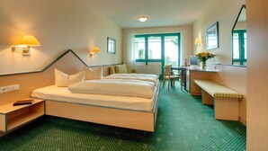 Una habitación de hotel con una cama, mesitas de noche, un escritorio y una silla.