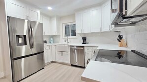A modern kitchen with white cabinets, stainless steel appliances, and a wooden countertop. -  Beachy Keen Cottage B!  Just Steps from Indian Rocks Beach! (Indian Rocks Beach)