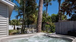 A hot tub in a backyard with palm trees and a wooden fence. -  Beachy Keen Cottage B!  Just Steps from Indian Rocks Beach! (Indian Rocks Beach)