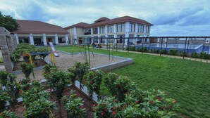 A hotel with a swimming pool, a playground, and a well-maintained lawn. - Spoorti Resort and Club (Bijapur)
