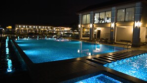 A swimming pool with a wooden deck and a glass balustrade. - Spoorti Resort and Club (Bijapur)