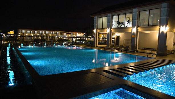 A swimming pool with a wooden deck and a glass balustrade. - Spoorti Resort and Club (Bijapur)