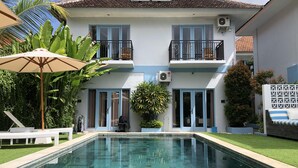 A two-story house with a swimming pool, a balcony, and a covered patio area.