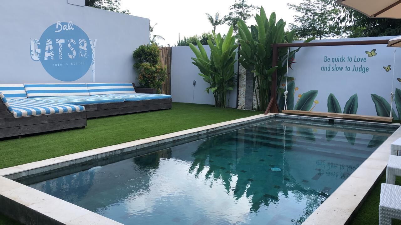 A pool area with a blue and white striped lounge, a wall with a logo and text, and a mural with a quote.