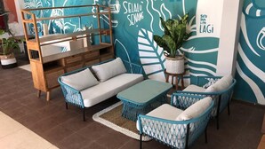 A cozy seating area with a sofa, two armchairs, and a small table, all with blue and white patterns. A wooden shelf unit is also visible.