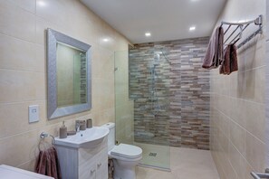 A modern bathroom with a glass-enclosed shower, a vanity with a mirror, and a toilet. - Gorgeous 1BR Apartment close to Amenities (Msida)