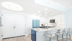 Una cocina moderna con armarios blancos, un refrigerador azul y una isla central con taburetes de bar.