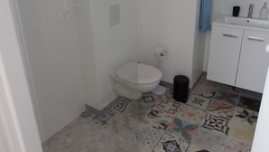Een badkamer met een douche, toilet en wastafel.