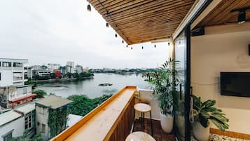 Un balcon avec une balustrade en bois, un petit tabouret et des plantes en pot.