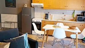 A compact living space with a kitchenette, a dining area with a table and chairs, and a sofa with cushions. - Sofie's Choice Mytilini (Lesvos)