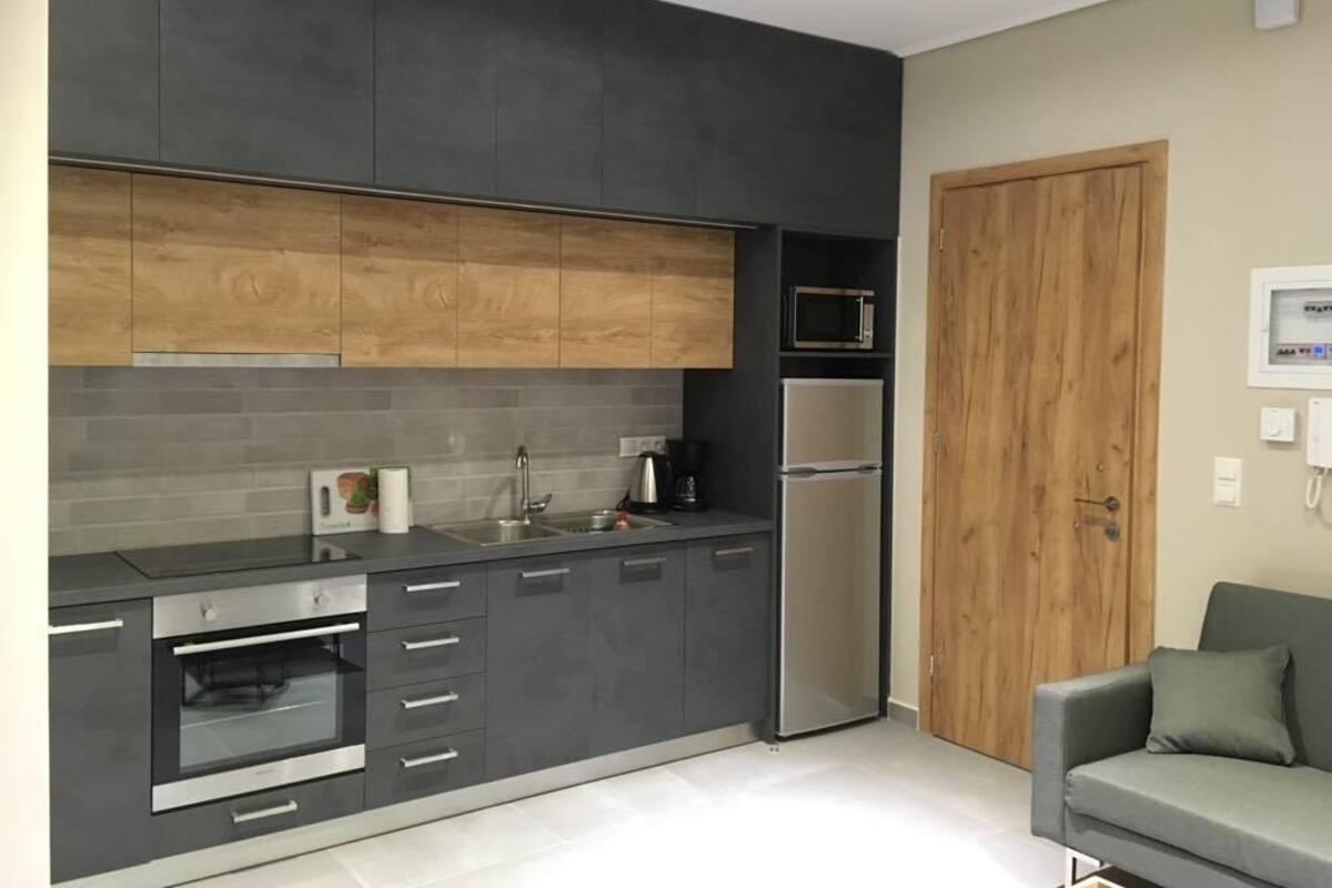 A modern kitchen with dark cabinetry, a built-in oven, a microwave, and a refrigerator.