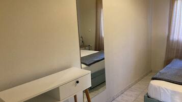 Una camera da letto con un letto, un comodino, uno specchio e una finestra con tende.