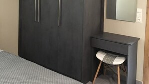 A bedroom with a large wardrobe, a bedside table, a chair, and a mirror. - Sofie's Choice Mytilini (Lesvos)
