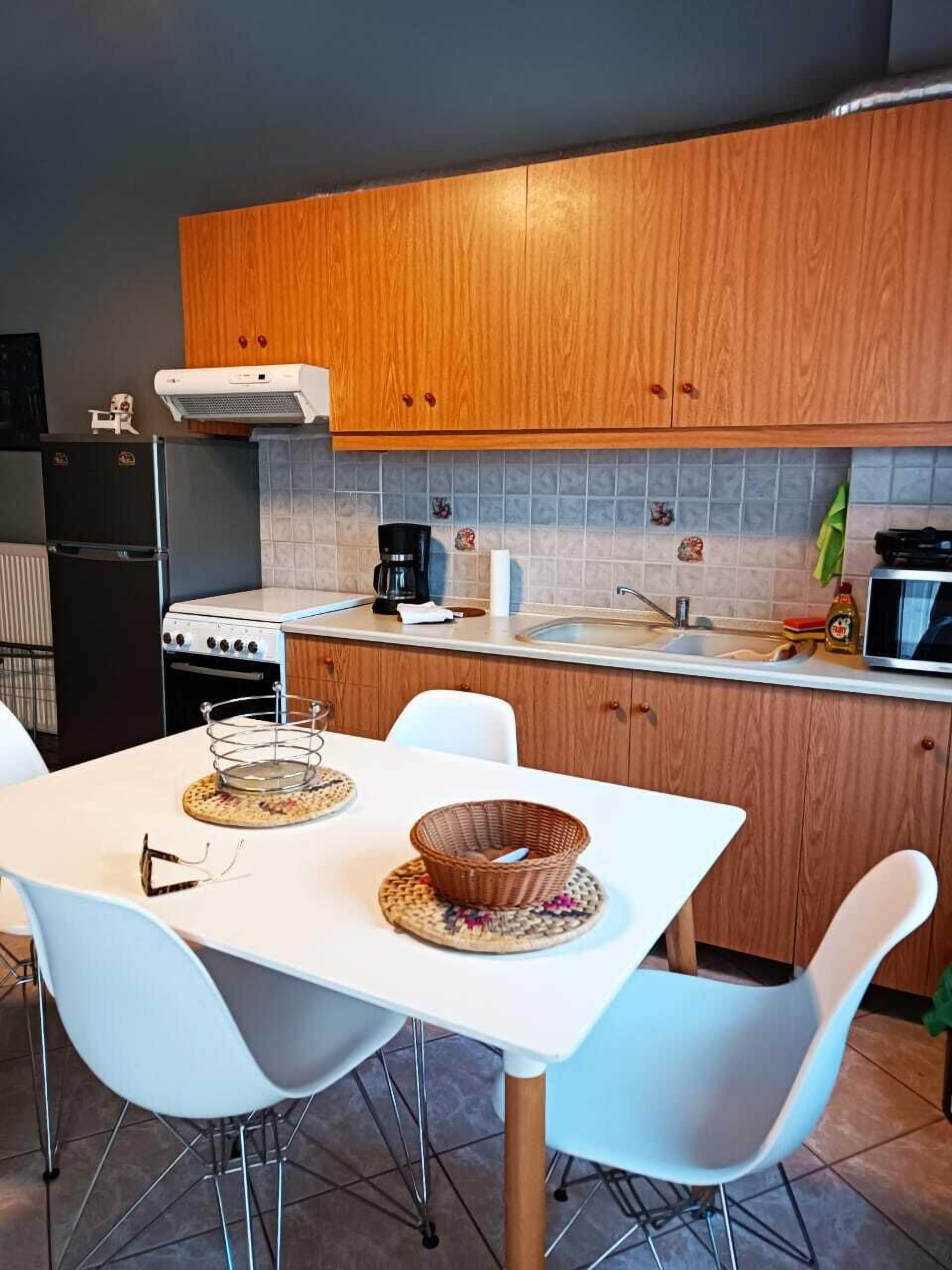 A modern kitchen with wooden cabinets, a white countertop, and a dining table with white chairs.