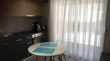 Una cocina moderna con armarios oscuros, un lavamanos de acero inoxidable y una mesa redonda con manteles individuales azules.