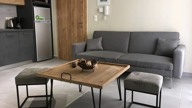 A modern kitchen with a grey sofa and a wooden table in the living area. - Sofie's Choice Mytilini (Lesvos)
