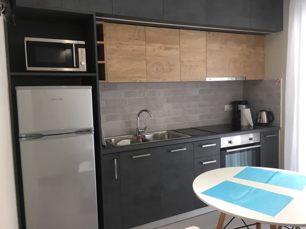 Une cuisine moderne équipée d’un four à micro-ondes encastré, d’un réfrigérateur, d’un évier et d’une machine à café.