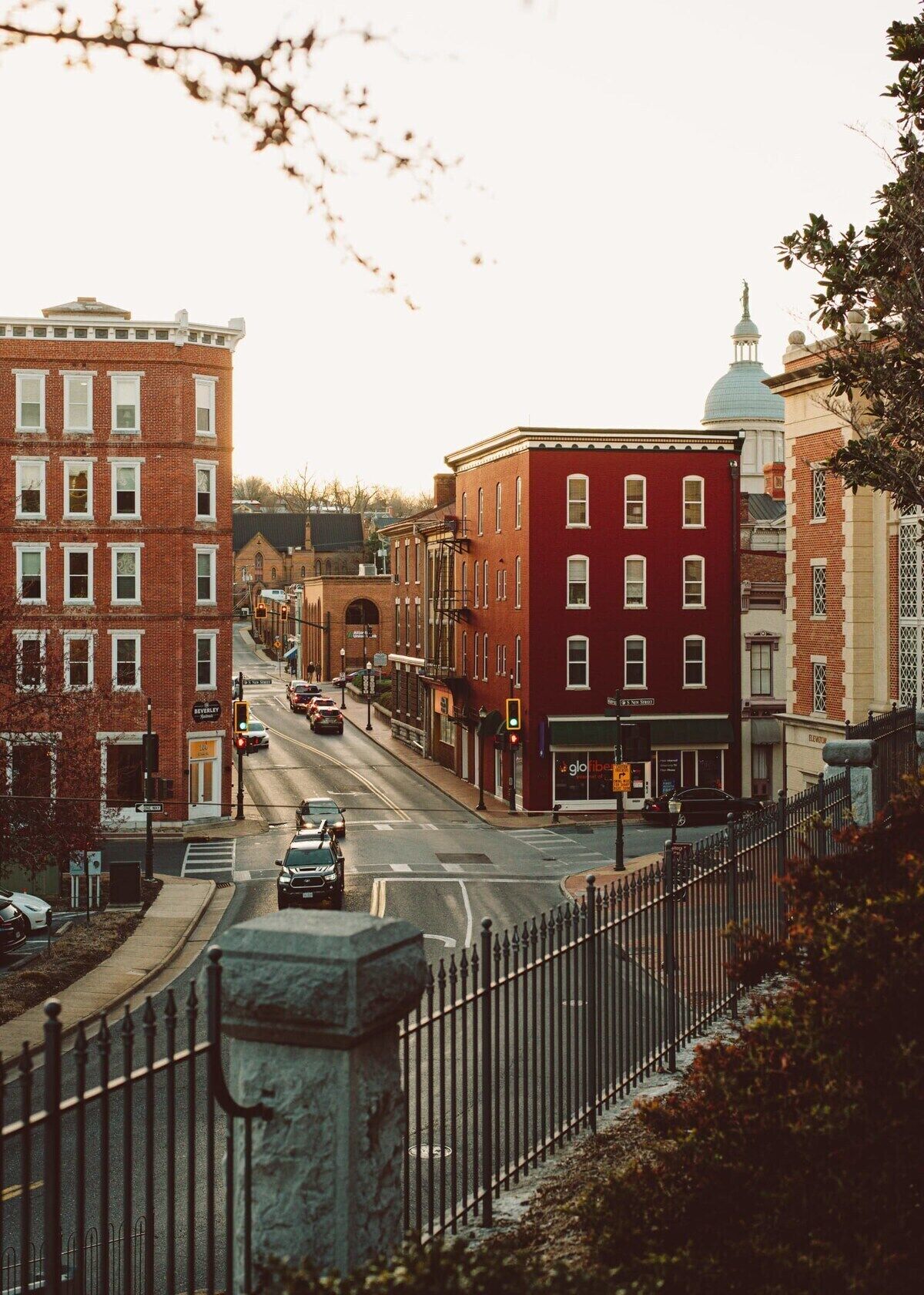 A street view with a red brick building, a blue dome structure, and a black metal fence.