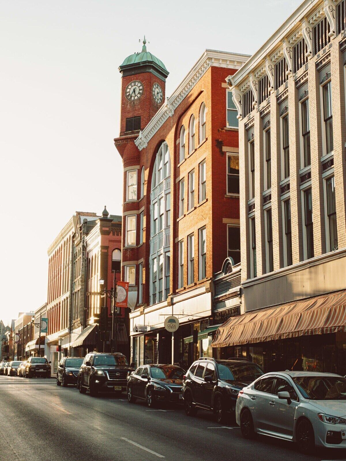 A street view with historic buildings, a clock tower, and parked cars.