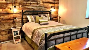 A bedroom with a wooden headboard, a bed with patterned bedding, a bedside table with a lamp, and a small bookshelf. - Carbondale Townhome with A/C, WiFi, and Backyard (Carbondale)