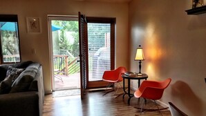 A living room with a sofa, two rocking chairs, a table with a lamp, and a sliding glass door leading to a balcony. - Carbondale Townhome with A/C, WiFi, and Backyard (Carbondale)